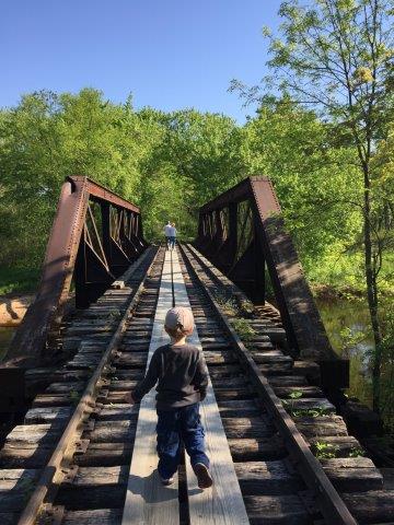 Photo of child looking across a bridge. Taken during Tiffany Bottoms train ride Field Trip. Photo by Charity Hohlstein.