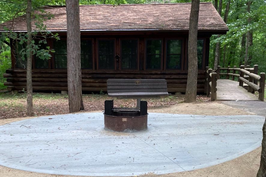 A paved area around a campire pit in front of a cabin