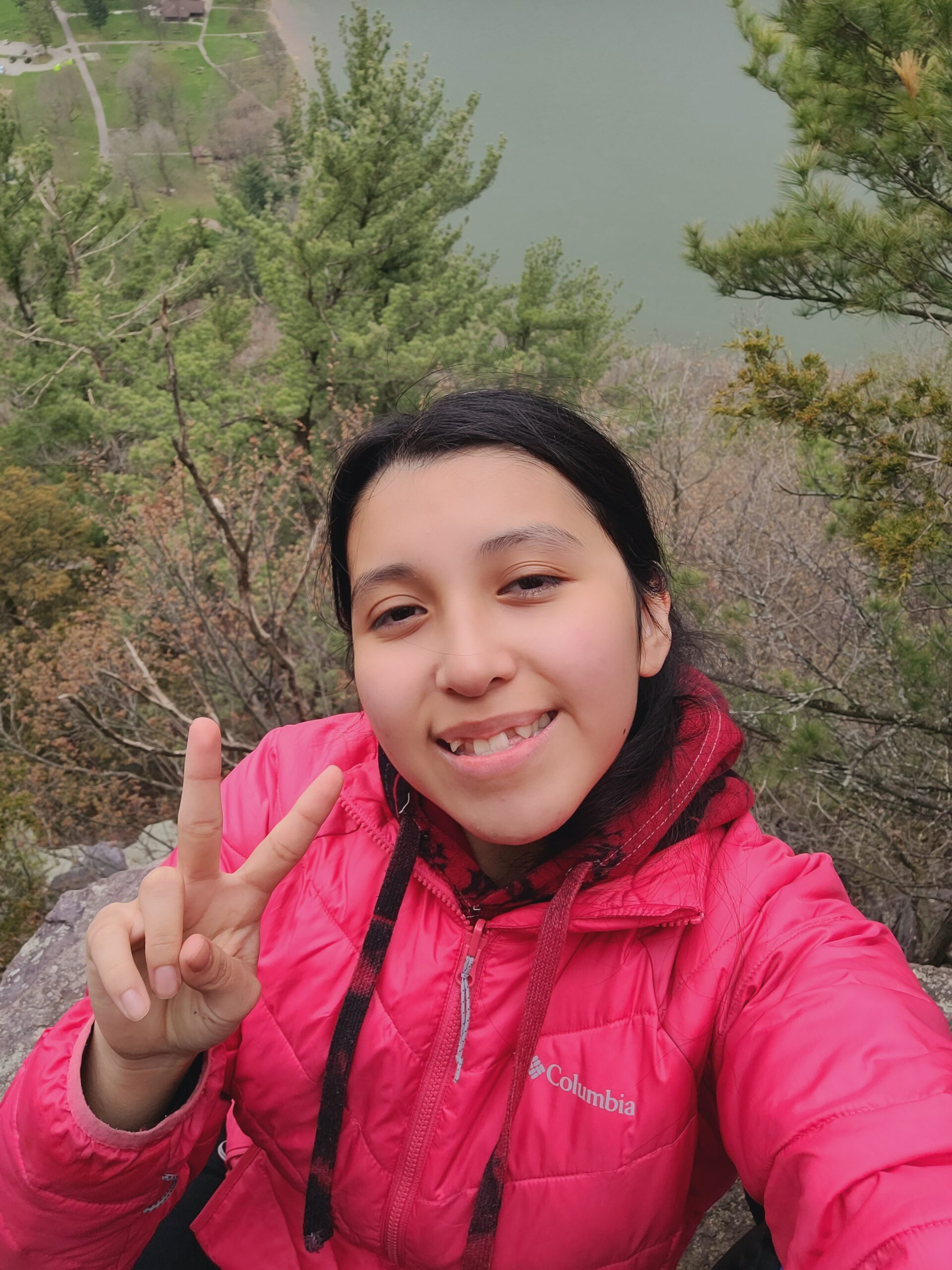 2024 Diversity in Conservation Internship cohort member holding up a peace sign while on a hike