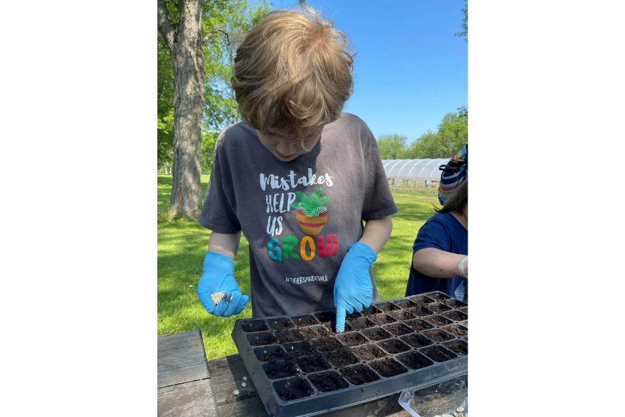 SOAR Thru Summer camper planting seeds in a tray of soil