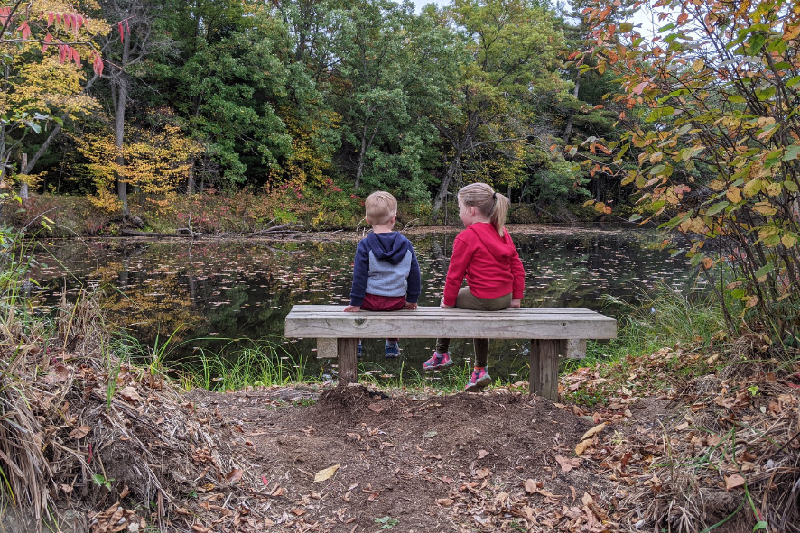 Two children sitting on a bench overlooking the Wisconsin River during autumn