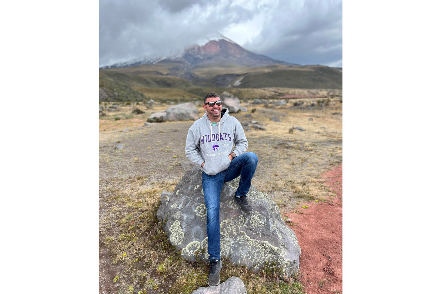 Ricardo sitting on a rock in front of the Cotopaxi volcano in Ecuador