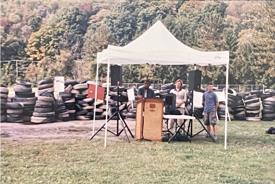 People standing underneath a tent with piles of tires behind them