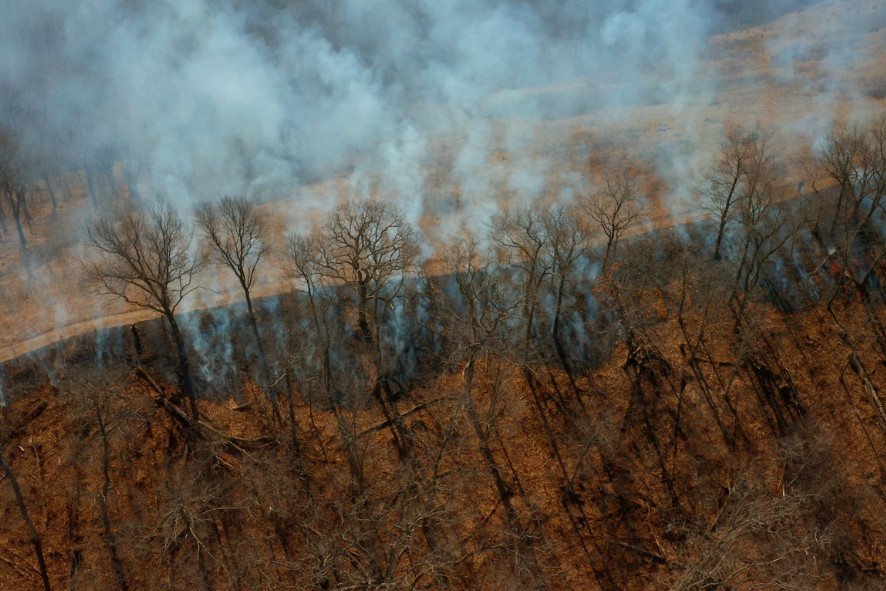 an aerial view of smoke coming off of a landscape after a prescribed burn