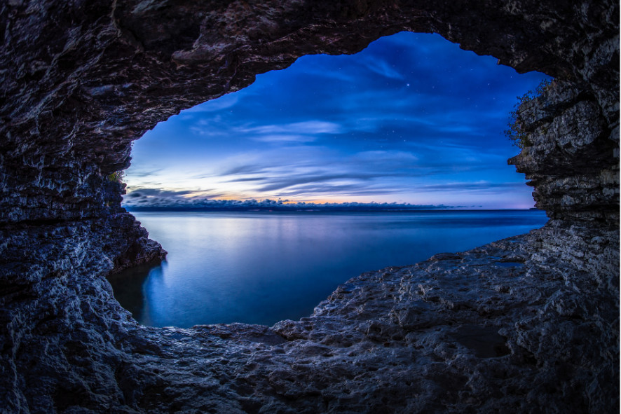 view of a lake at dusk from the inside of a cave, 2024 photo contest grand prize winner