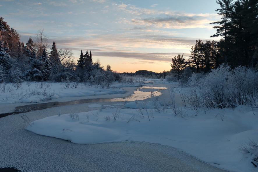 A partially frozen river and a shoreline covered in snow at one of Wisconsin’s state parks